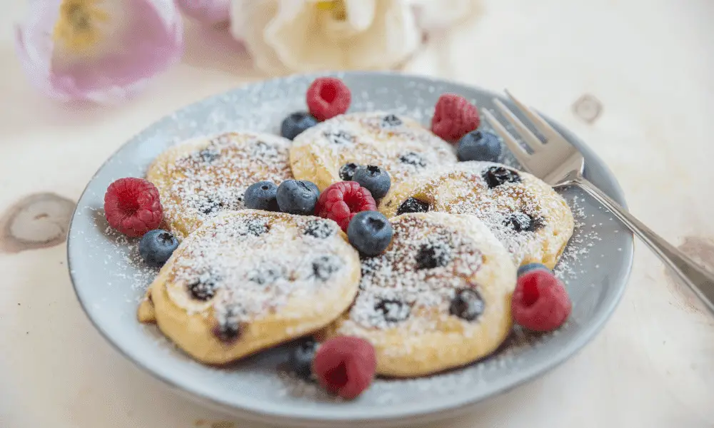 Golden-brown lemon blueberry pancakes served on a plate, accentuated by the vibrant colors of fresh blueberries