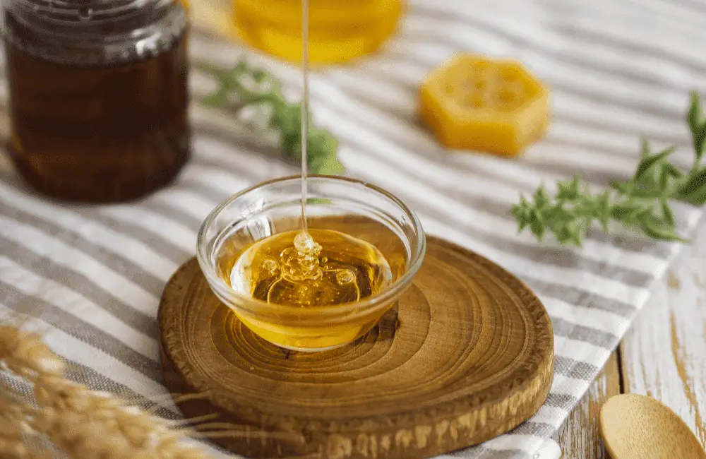 Golden, thick honey flowing smoothly into a mixing bowl, ready to blend with other ingredients.