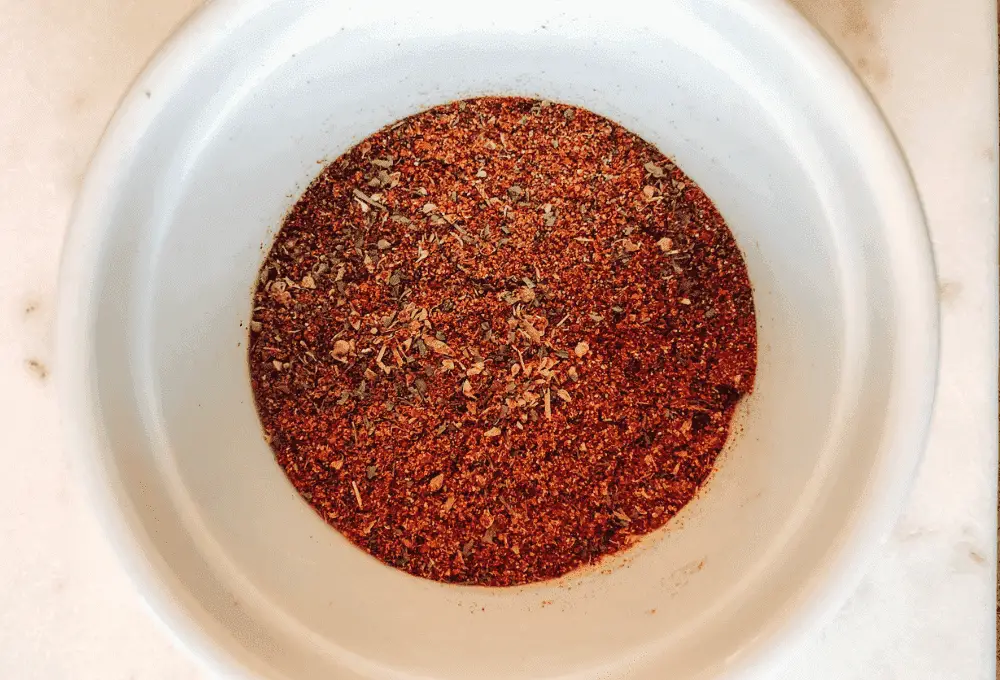 Hands blending the various spices and herbs in a bowl, capturing the moment of creating the perfect chicken taco seasoning.