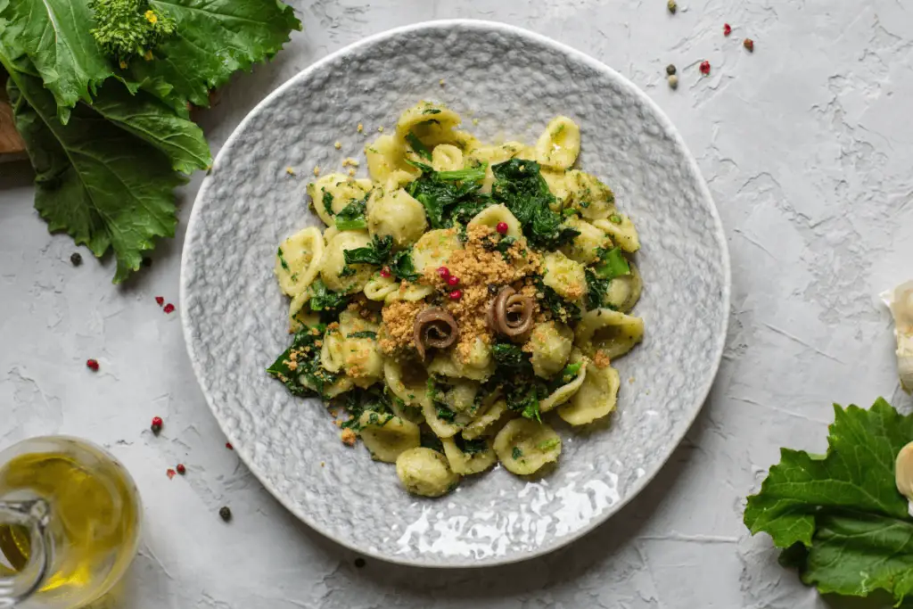 Bowl of Orecchiette with Pistachio Pesto, garnished with grated Parmesan and chopped pistachios, served in an Instant Pot.