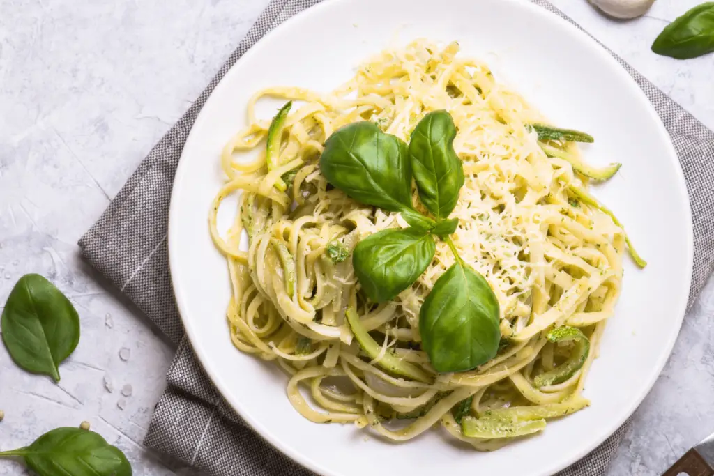 Delicious Fried Zucchini Spaghetti served in a white dish, garnished with fresh basil and Parmesan cheese.