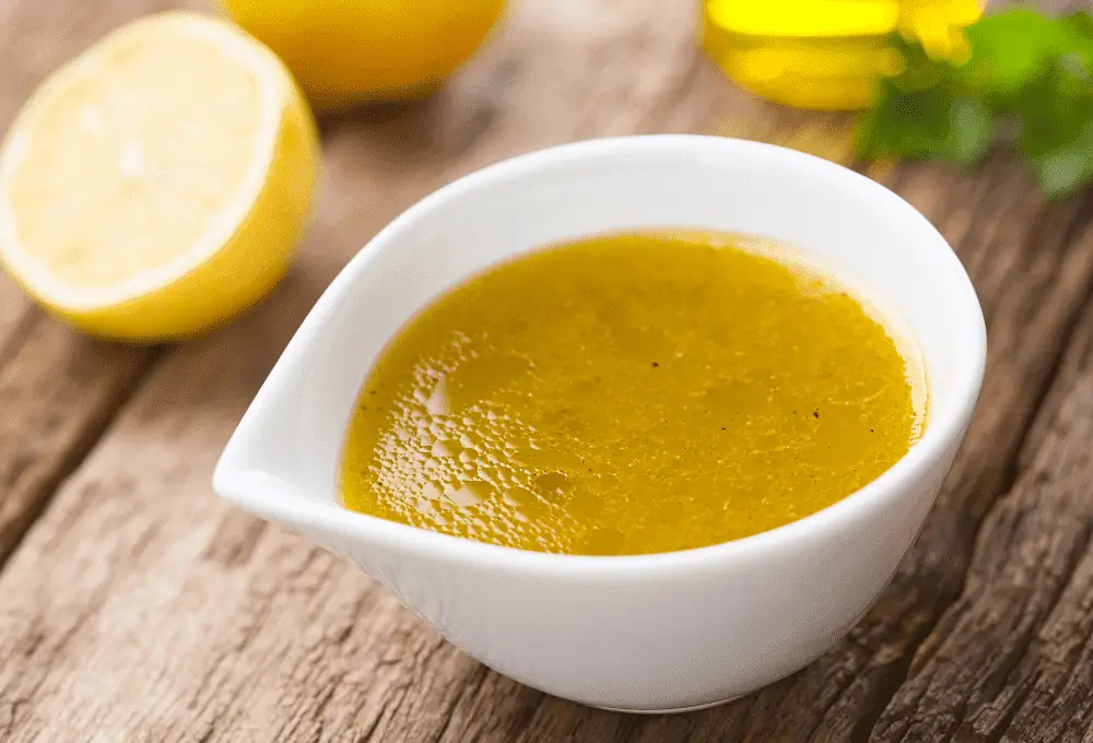 Bowl with olive oil being whisked with fresh lemon juice.