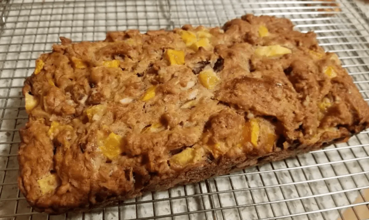 Freshly baked mango bread loaf captured on a phone, with a golden-brown crust and moist texture visible.