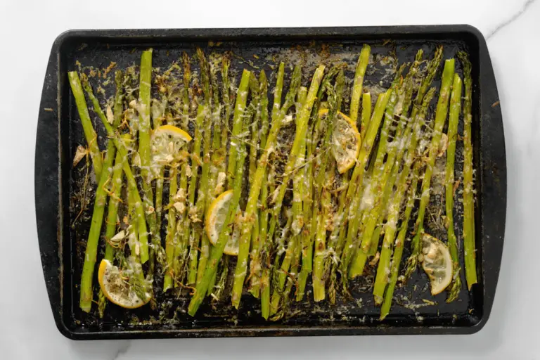 A beautifully plated serving of roasted asparagus with Parmesan and lemon wedges