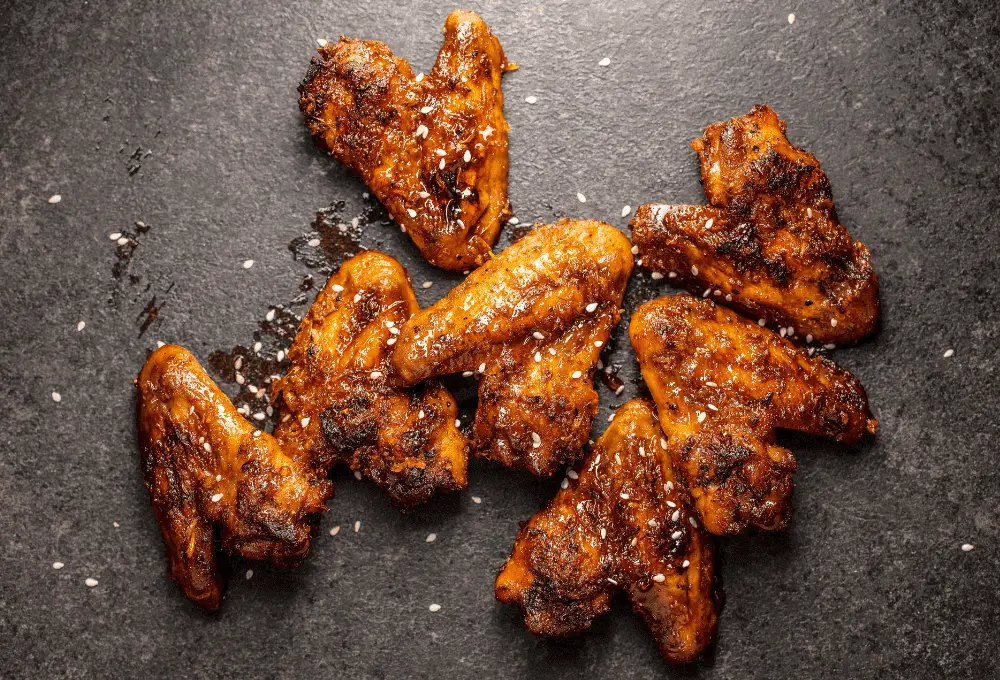 Close-up of a crispy chicken wing, highlighting the texture and sprinkled with toasted sesame seeds