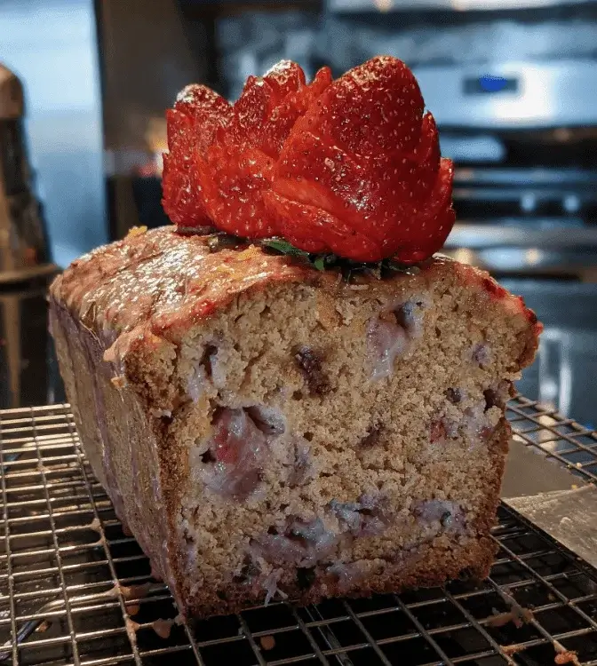 Strawberry bread drizzled with glossy strawberry glaze, topped with fresh strawberry slices.