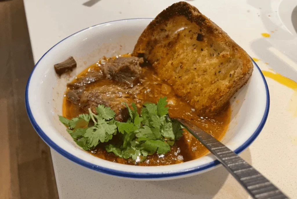 Gluten-free garlic bread dipped into a bowl of creamy tomato soup, the perfect comfort food duo.