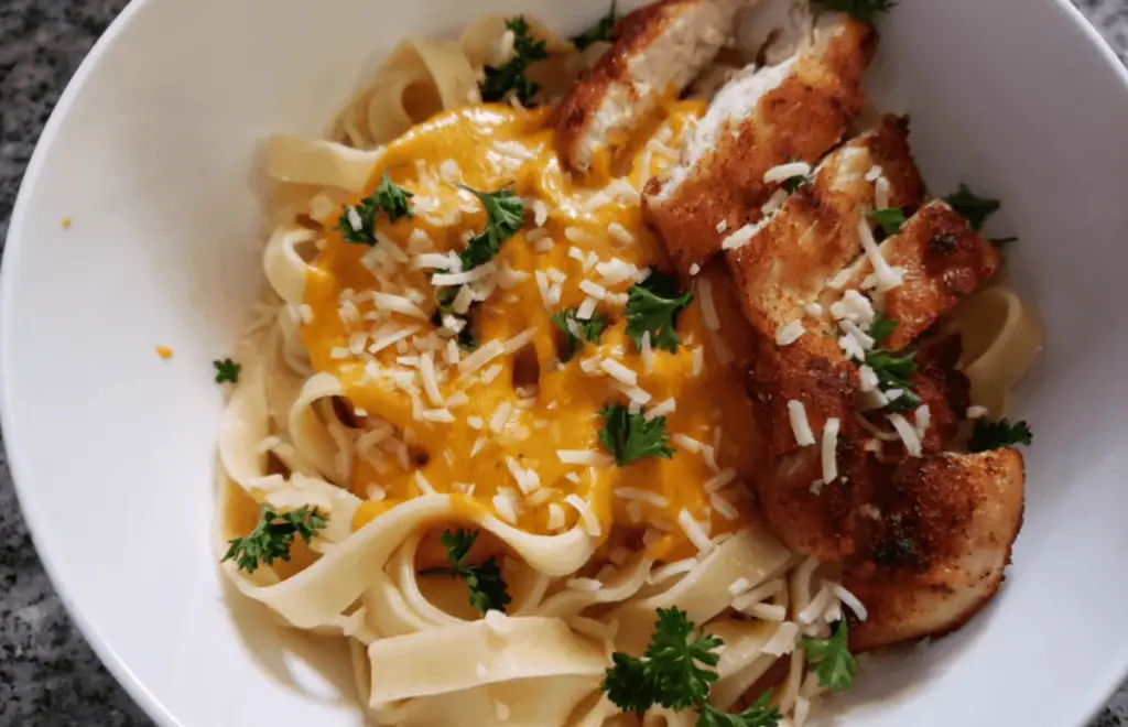 Creamy pumpkin pasta sauce generously coating spaghetti, garnished with fresh herbs and grated Parmesan.