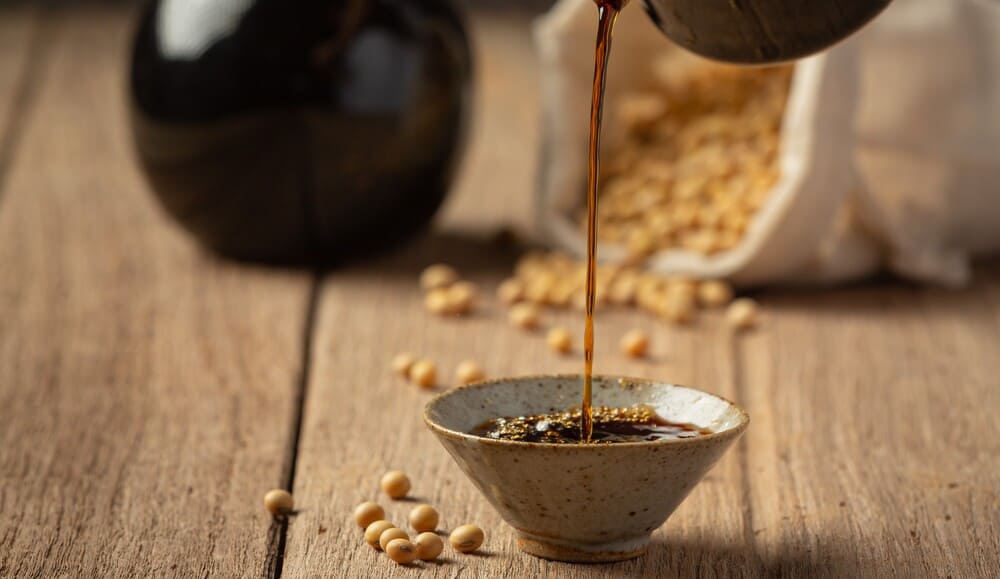 Dark, savory soy sauce being poured over golden honey, creating a beautiful contrast and the start of a delicious marinade.