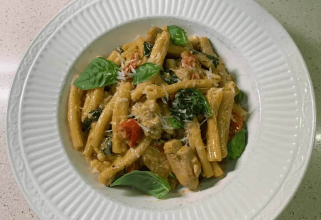 Close-up of Creamy Tomato Spinach Pasta garnished with fresh basil and grated parmesan.