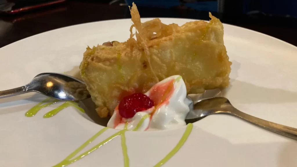 A yummy piece of Tempura Cheesecake with crispy outside and creamy inside, on a white plate.