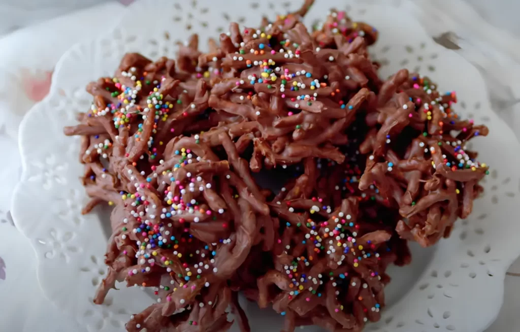 Close-up of freshly baked No Bake Haystack Cookies on a white plate with sprinkles.