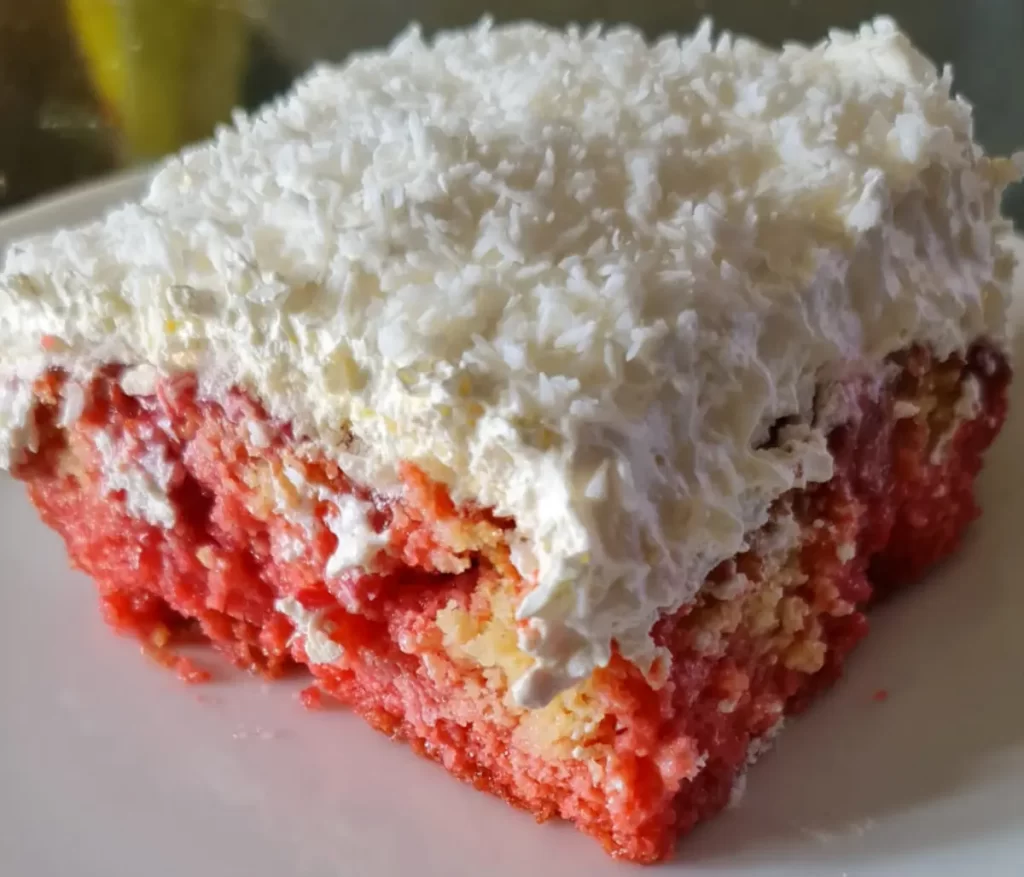 Delicious Raspberry Zinger Poke Cake topped with Cool Whip and shredded coconut, served on a white plate.