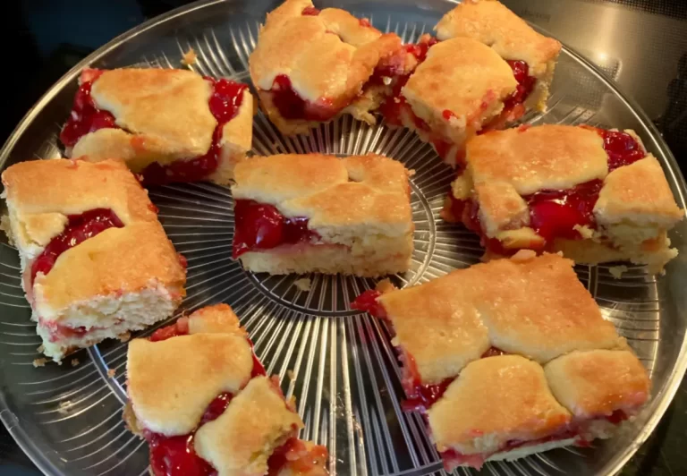 Delicious Cherry Bars with a golden crust, sweet cherry filling, and drizzled glaze, placed on a transparent plate.