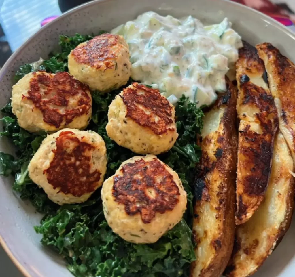 Plate of Greek Chicken Meatballs garnished with fresh herbs, served with tzatziki sauce on the side.