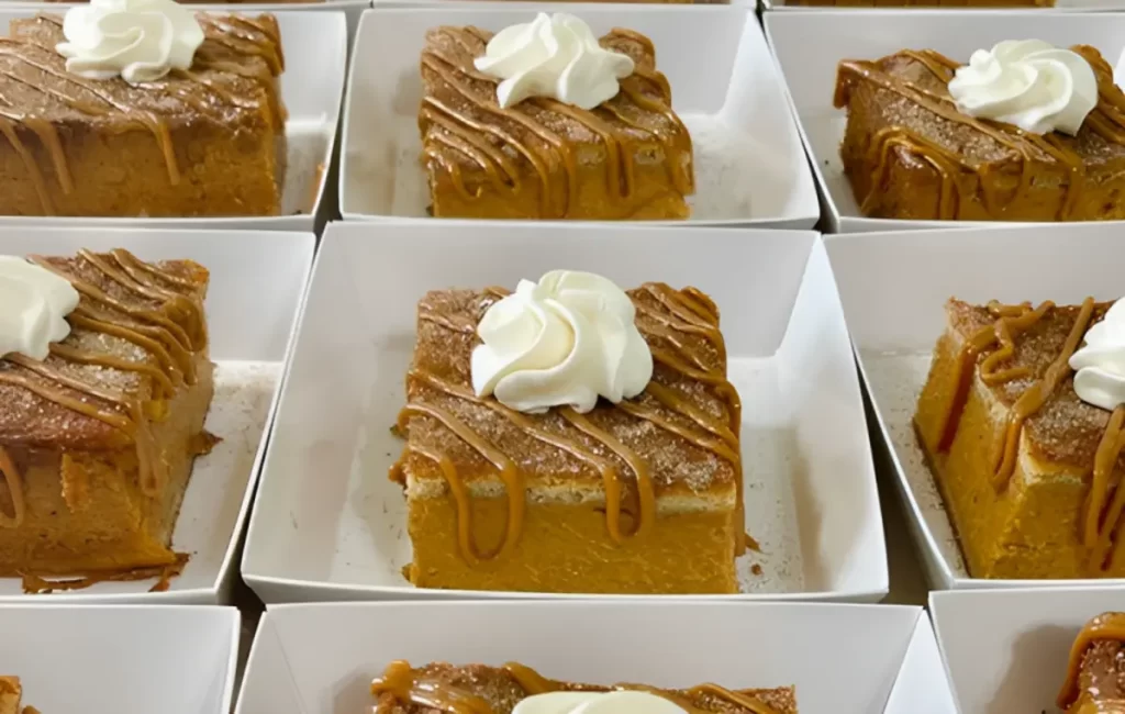 Delicious pumpkin pie bars with a smooth filling and a shortbread crust, topped with whipped cream and a sprinkle of cinnamon.