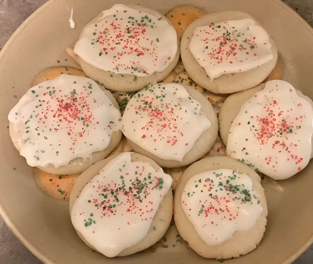 Freshly baked sour cream sugar cookies arranged on a plate with frosting.