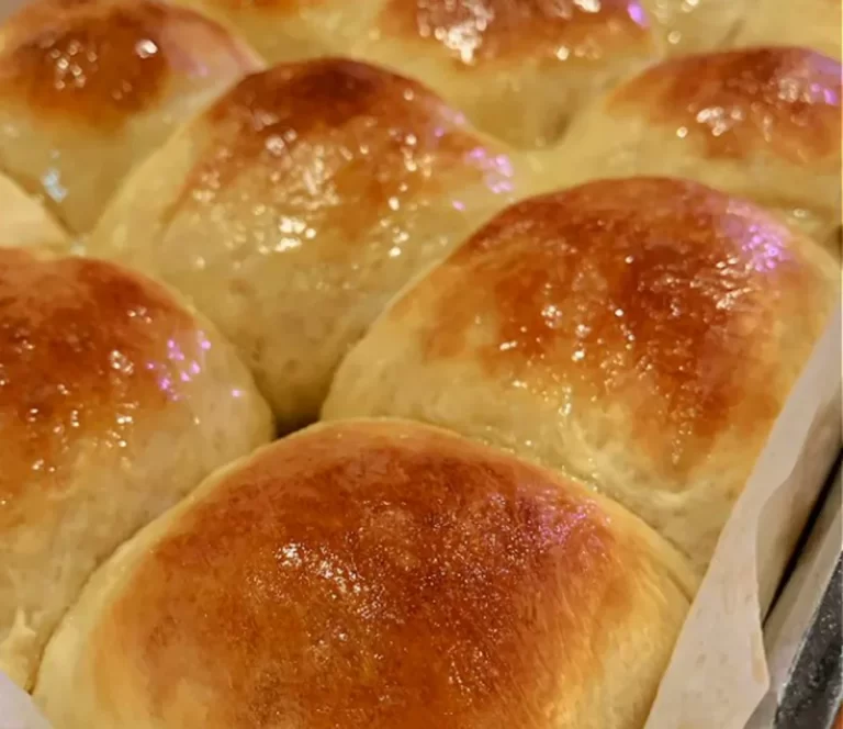 Freshly baked homemade dinner rolls arranged neatly on a serving plate, with a golden-brown crust and soft, fluffy texture, ready to be enjoyed with a meal.