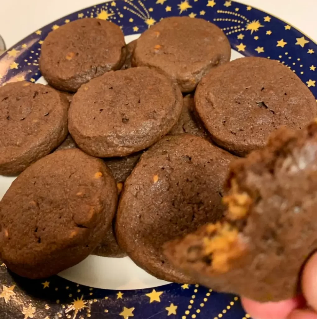 A plate of freshly baked Chocolate Peanut Butter Cup Cookies, with melted chocolate chips and peanut butter cups visible in each cookie.