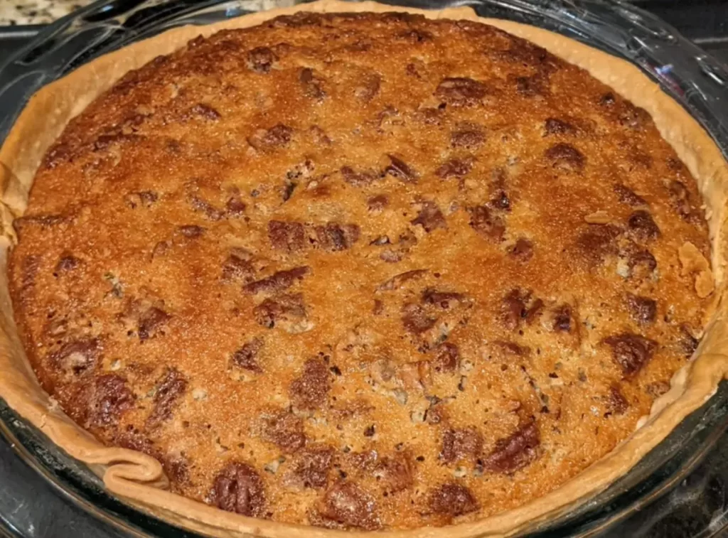 A slice of Buttermilk Pecan Pie served on a plate, showcasing its creamy filling and crunchy pecan topping.