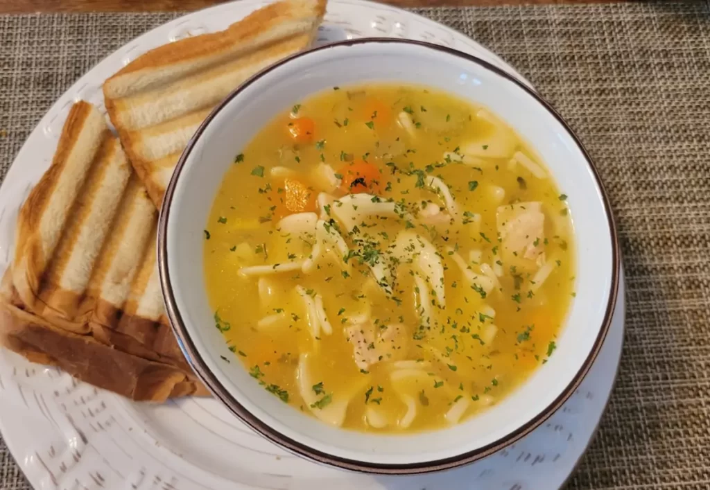 A bowl of creamy Crack Chicken Noodle Soup with melted cheese, tender chicken, and soft noodles.