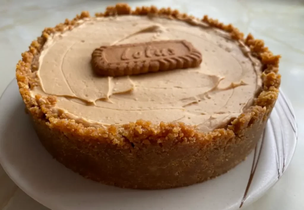 A creamy Lotus Biscoff Cheesecake with a golden biscuit base and a biscuit garnish on top.