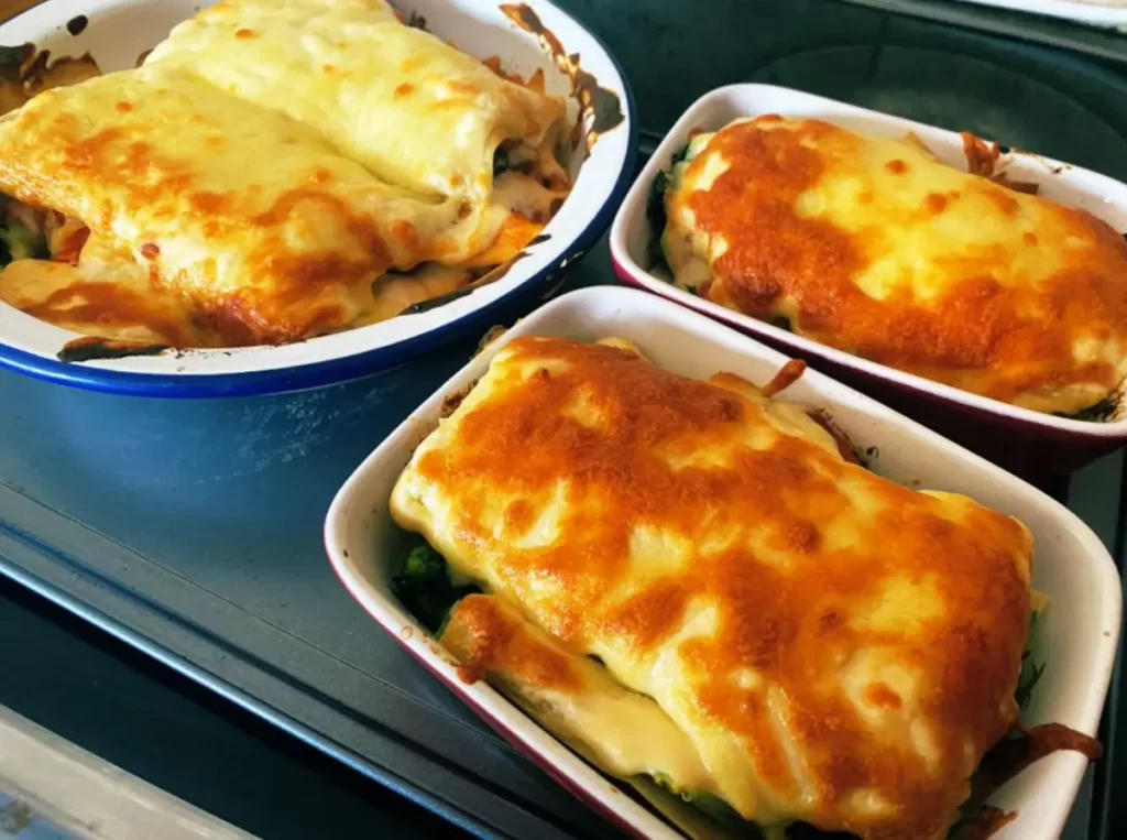 Baked chicken and broccoli lasagna with melted cheese in individual dishes.