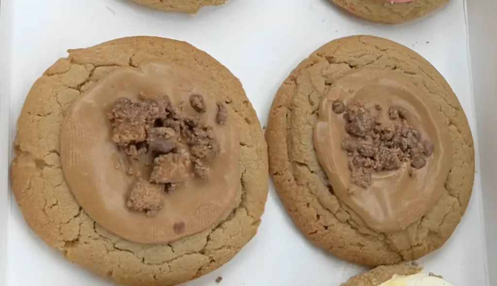 A close-up of a delicious Copycat Crumbl Reese's Peanut Butter Cup Cookie, showcasing its creamy peanut butter and rich chocolate toppings.