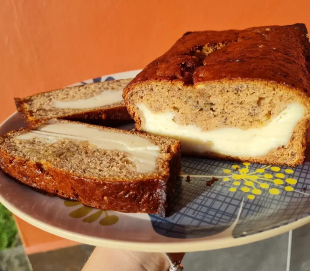 Slice of homemade banana bread with a creamy cheese filling on a plate