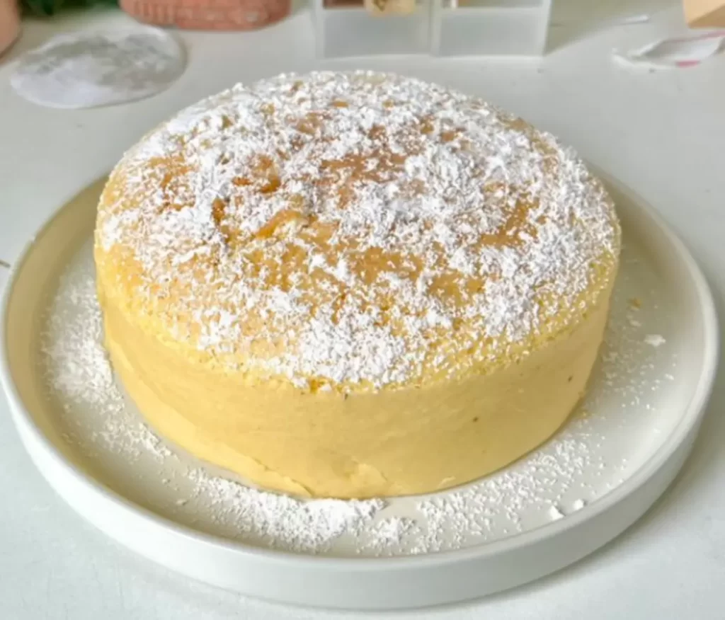 Japanese Cheesecake with a light, airy texture and a dusting of powdered sugar, served with fresh berries on a white plate.