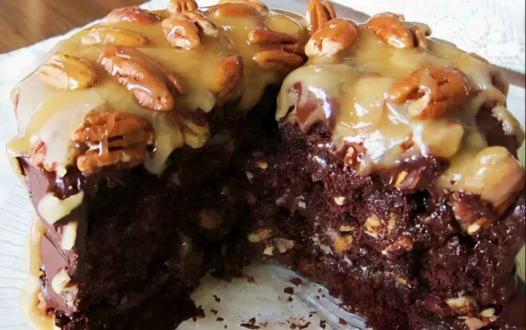 A slice of Turtle Cake showcasing layers of moist chocolate cake, gooey caramel, and crunchy pecans on a white plate.